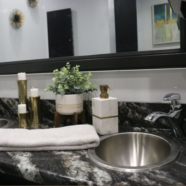 Granite vanity with a steel sink, towels and decor inside a restroom trailer