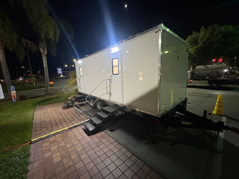 Lit restroom trailer at a nighttime event